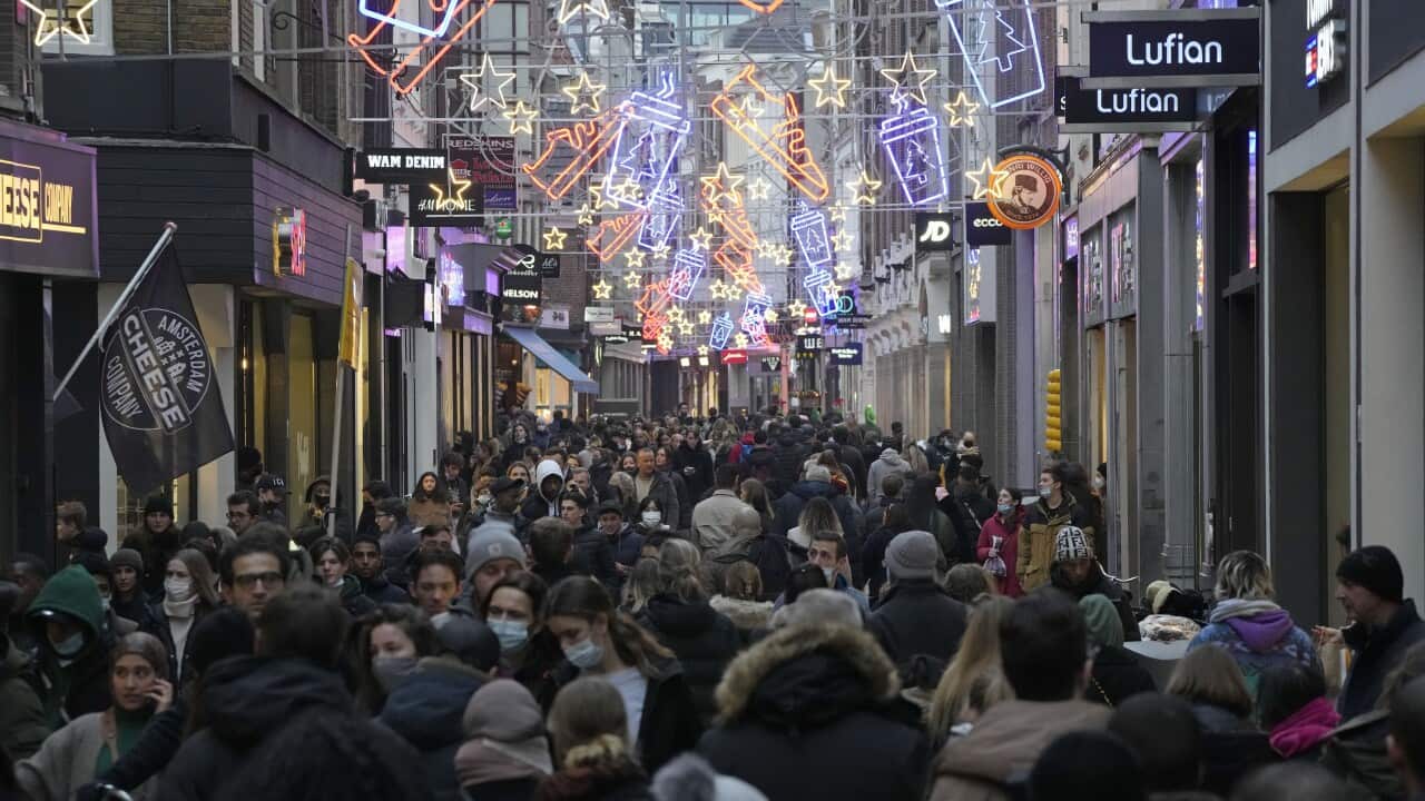 Crowds of people walk down a street in Amsterdam, the Netherlands.