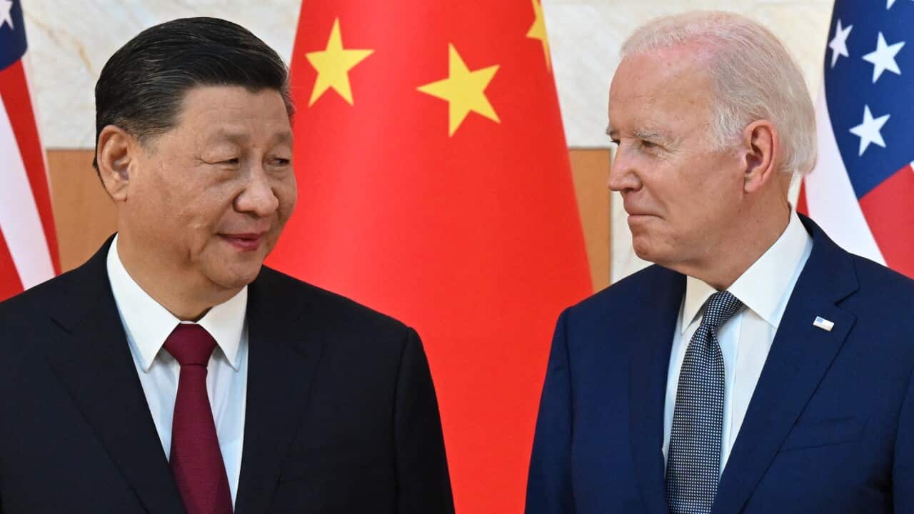 Xi Jinping and Joe Biden smile at each other in front of Chinese and US flags