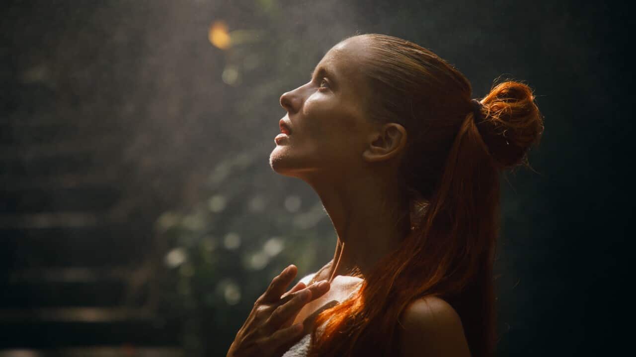 Thoughtful woman illuminated by sunlight amidst a serene outdoor setting