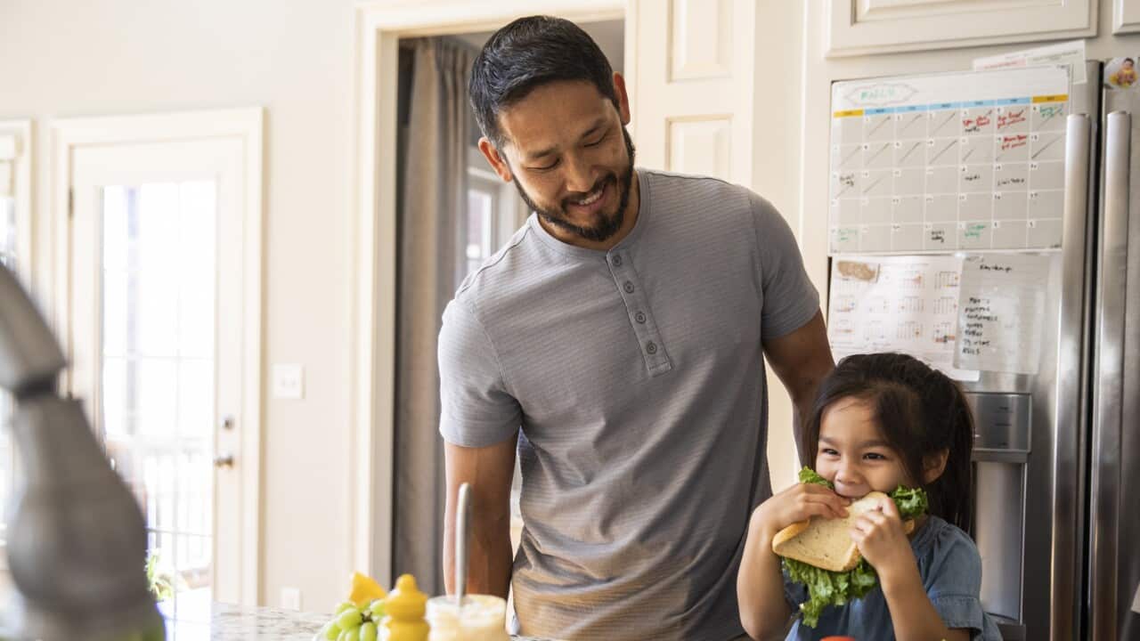 Father and daughter making sandwich in kitchen