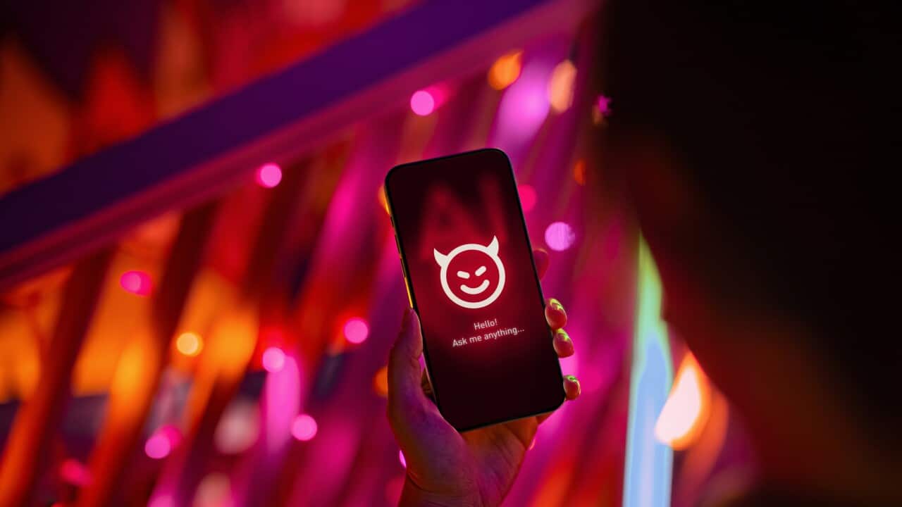 Female hand holding smartphone showing an evil with devil horn on her AI chatbot conversation app in the city. Illustrating the ideas around the risks and dangers of Artificial Intelligence (AI). The awareness and careful consideration of its implications