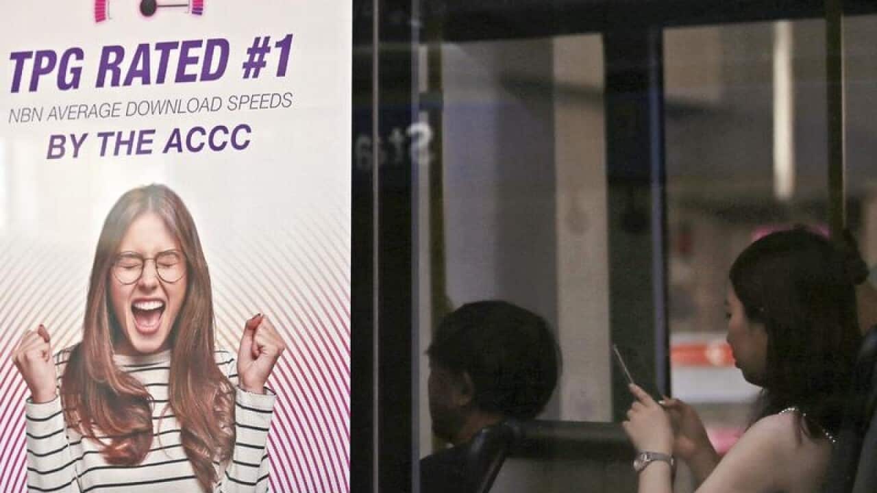 A woman uses a mobile device as she sits on a bus