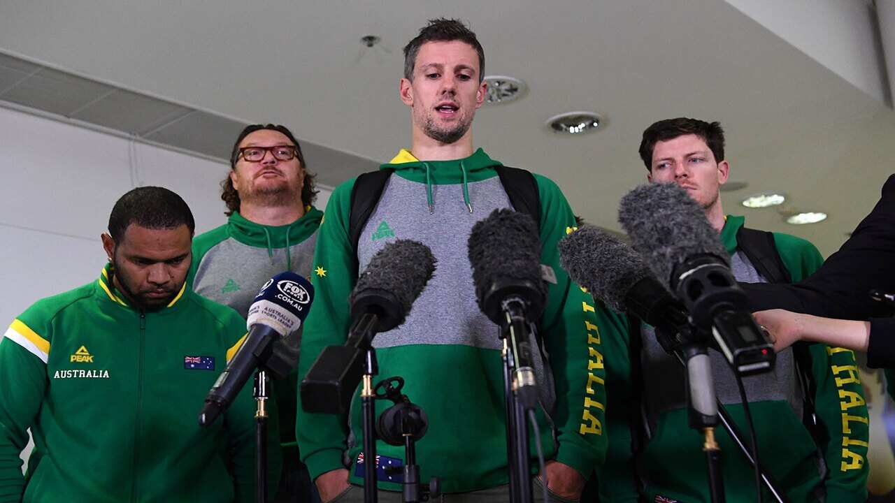 Daniel Kickert of the Boomers, the Australian national basketball team (centre), speaks to the media as he arrives at Brisbane airport, Wednesday, July 4, 2018