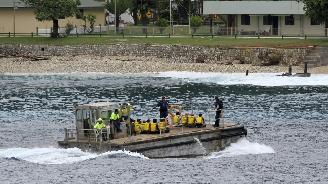 a group of asylum seekers are taken by barge to a jetty on Australia's Christmas Island