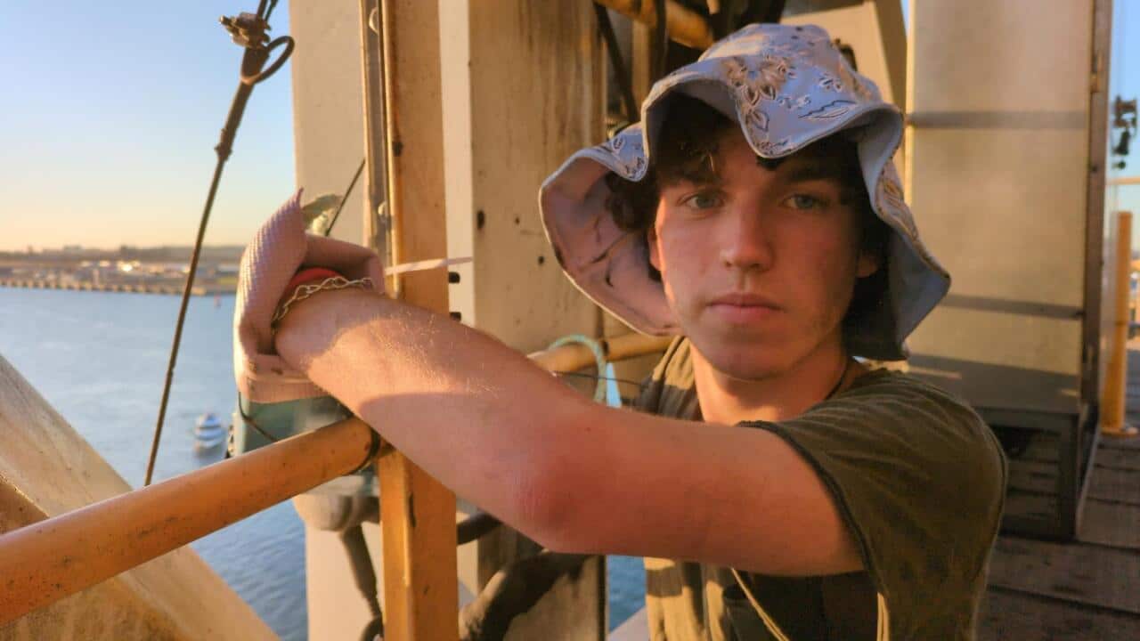 A young man with a chain around his hand on a vessel