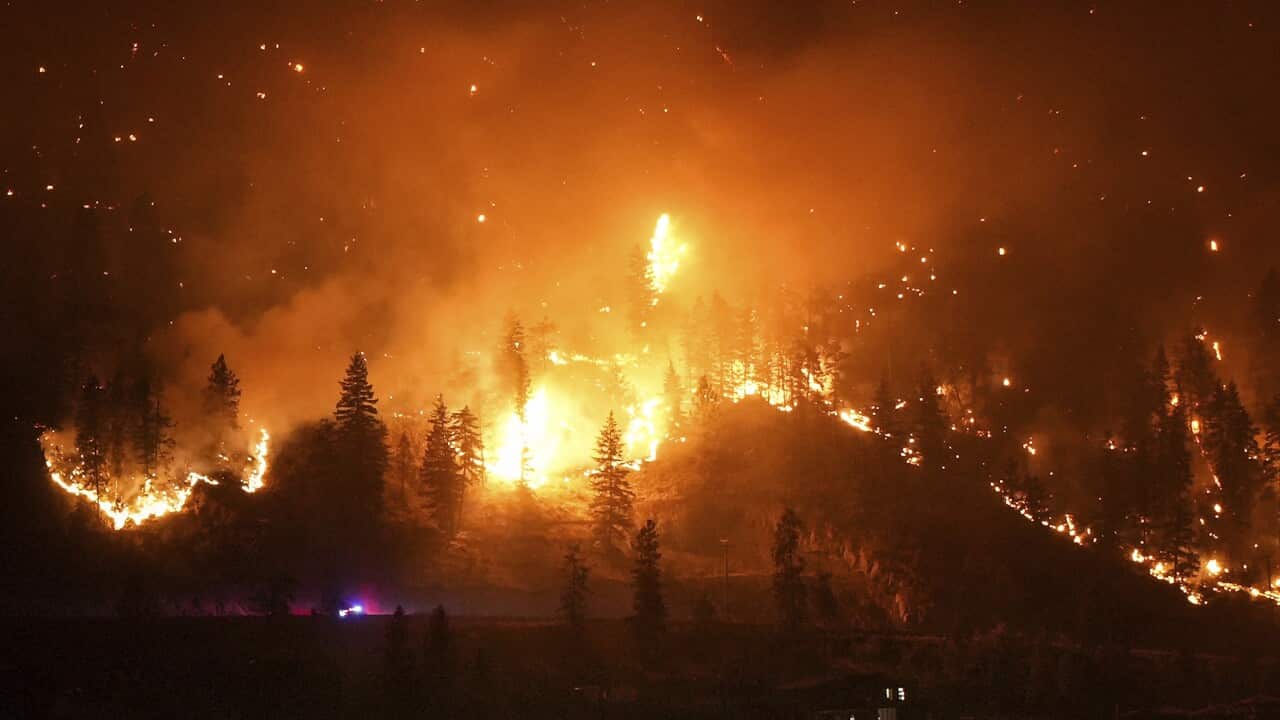 A fire burns on a mountain next to a lake