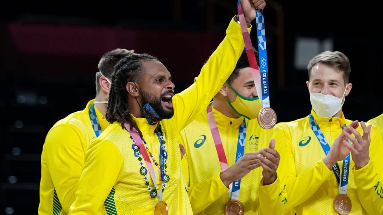 Australia's Patty Mills holds up a bronze medal for a teammate who was injured after beating Slovenia in the mens bronze medal basketball in Tokyo.