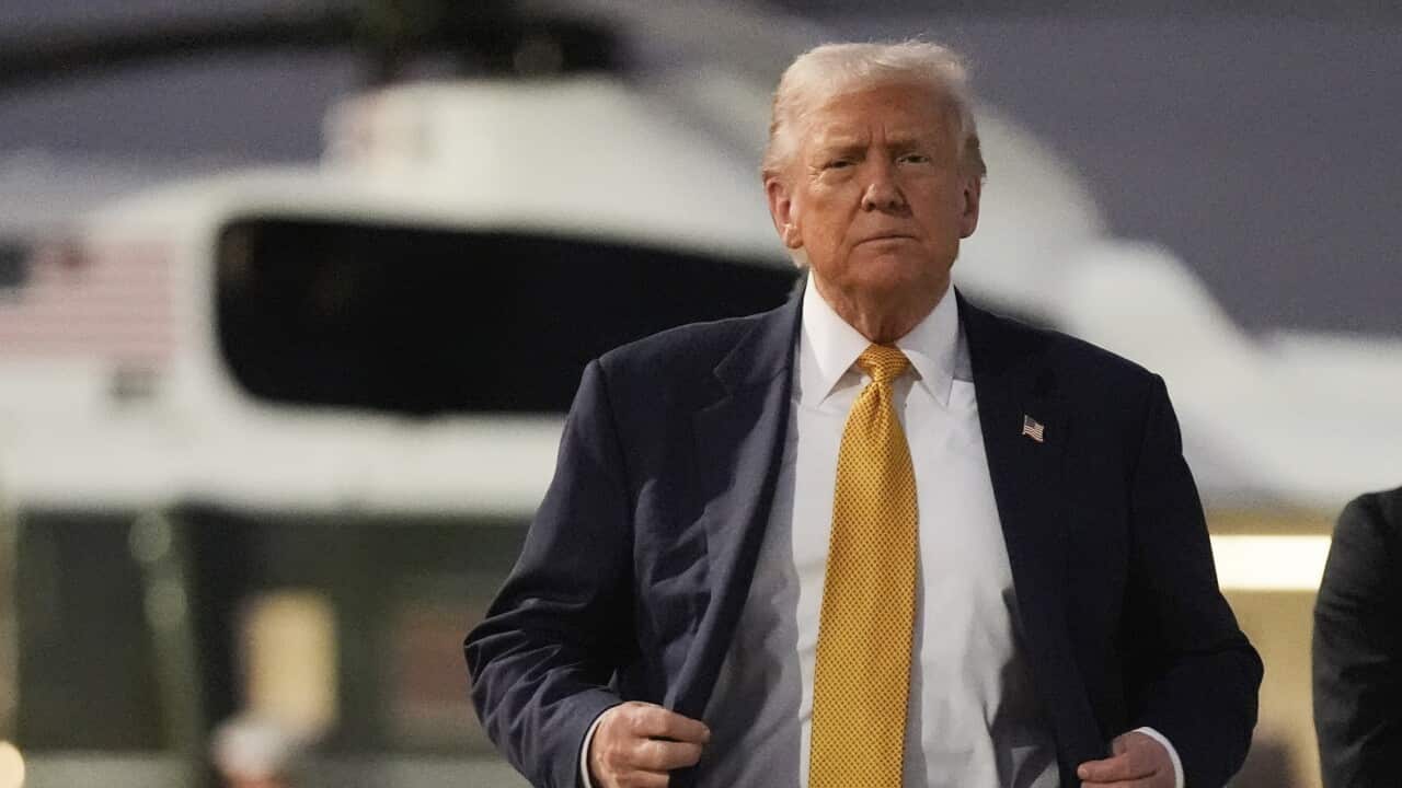 Donald Trump walking towards photographers with US Marine One behind him.
