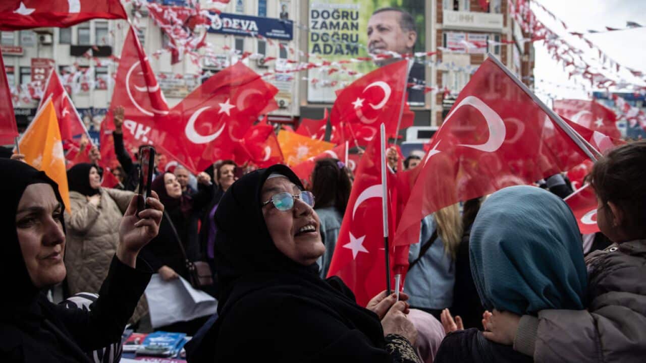 Supporters of Turkiye's President Recep Tayyip Erdogan wave flags during a campaign event.