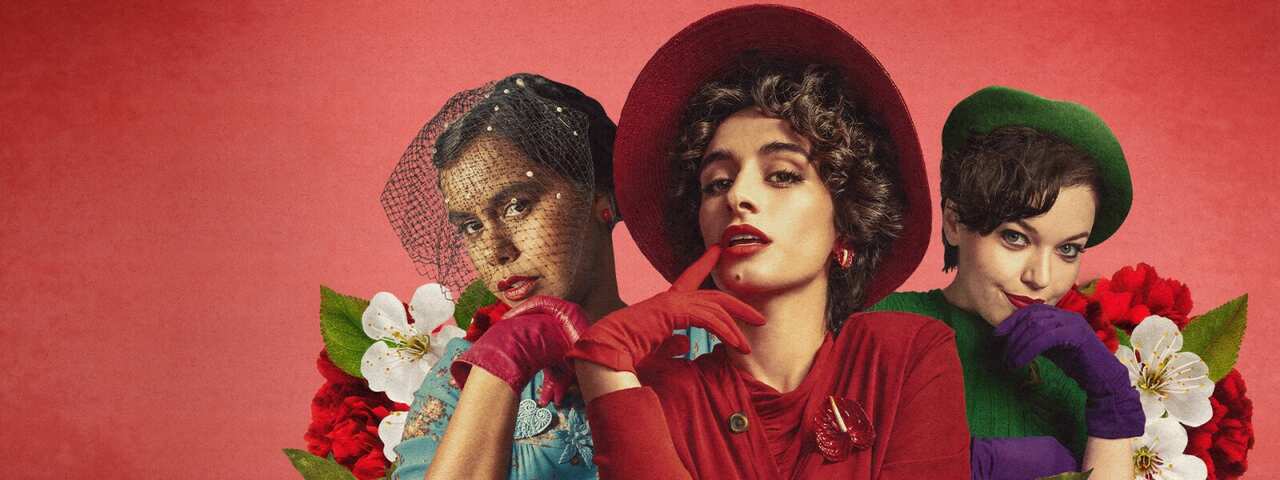 3 women in 1950s outfits pose surrounded by flowers