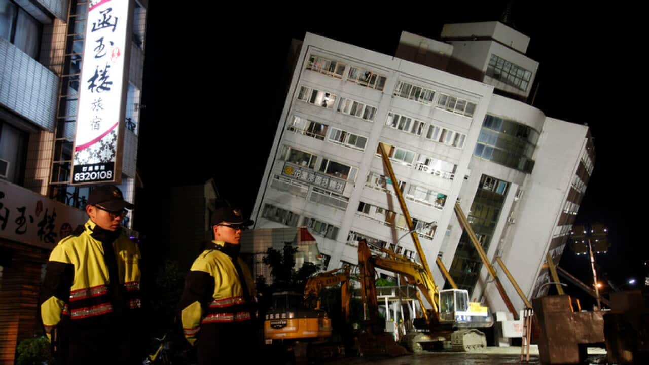 Two police officers guard outside of a collapsed apartment building in Hualien County, eastern Taiwan, Wednesday, Feb. 7 2018. A strong earthquake struck eastern Taiwan late Tuesday night.