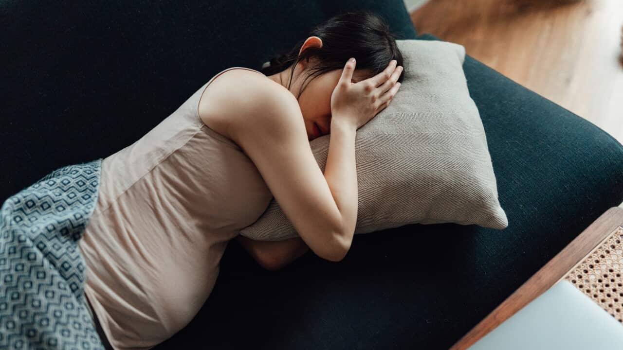 Pregnant Woman Covering Her Eyes With Hands While Laying On Sofa