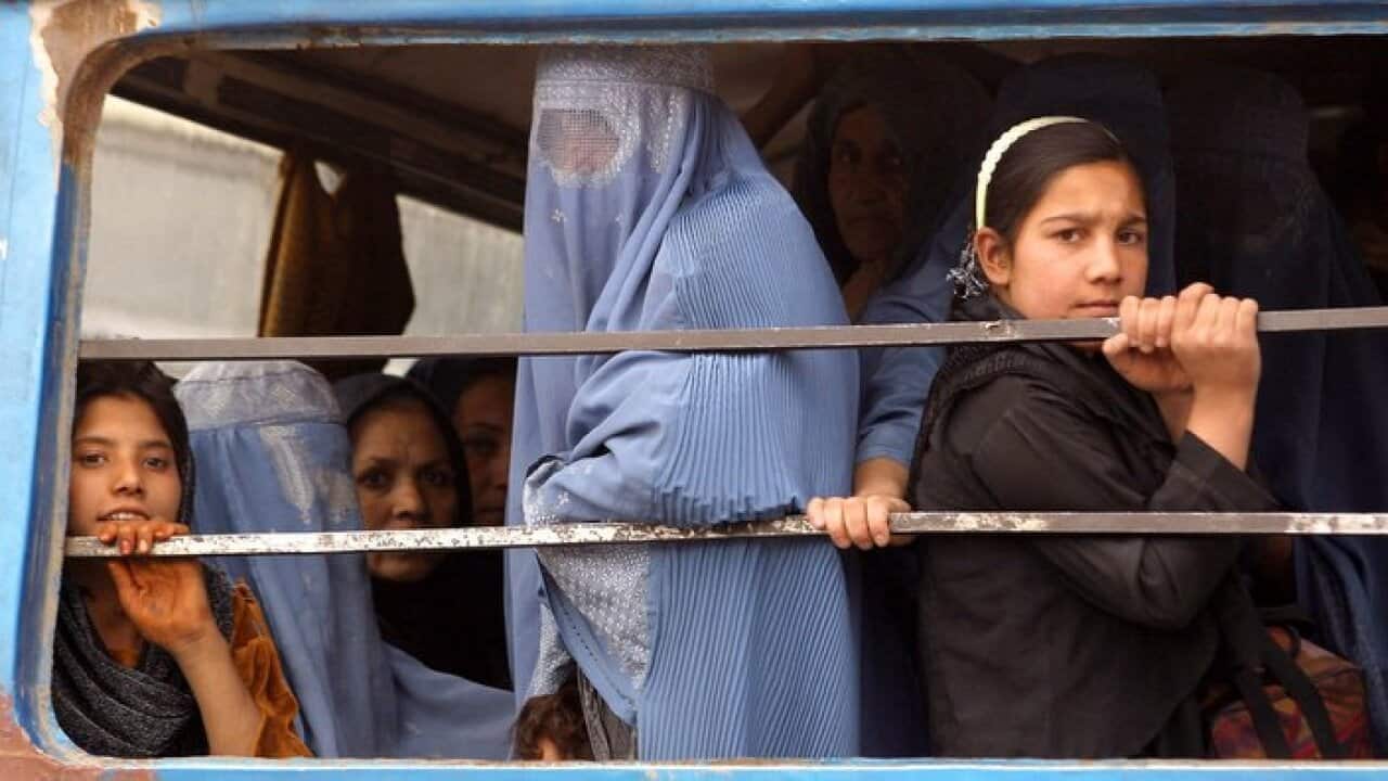 Afghan women look out from bus window as they are on their way back home from Kabul