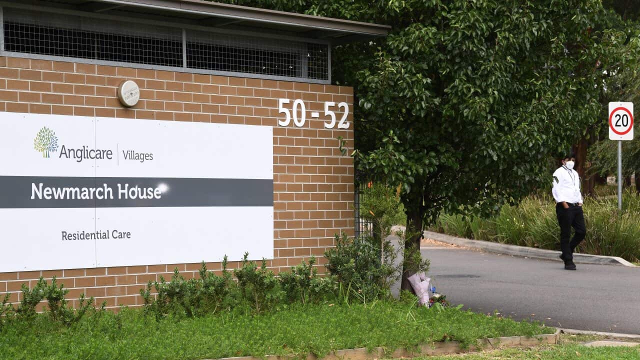 A security guard stands in the driveway as flowers are seen left at the entrance to Anglicare Newmarch House near Penrith.