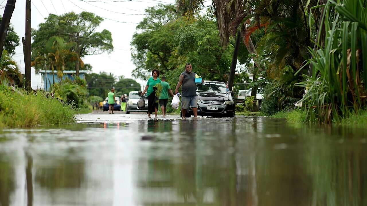 Residents wade through the flooded streets in Fiji's capital city of Suva on December 16, 2020, ahead of super Cyclone Yasa.