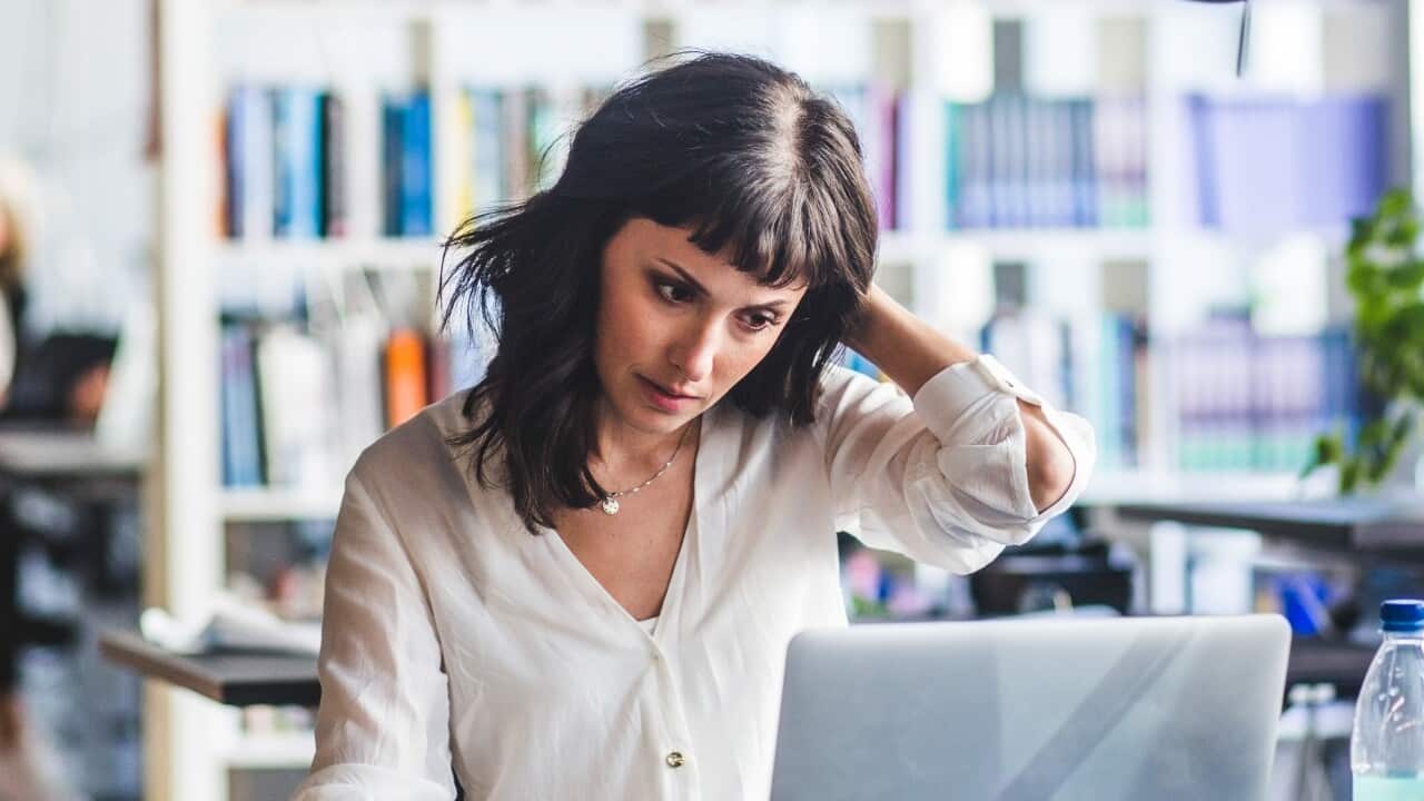 A woman looking at her laptop while sitting in office