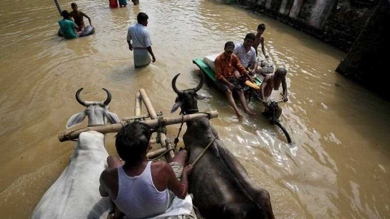 Indian commuters wade through a flooded street in Prafulla Nagar, some 120km north of Calcutta, India, 03 August 2015. (AAP)