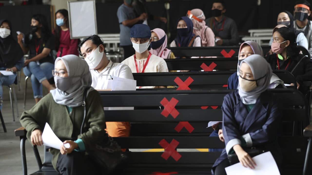 Employees sit spaced apart as they wait for their turn to take coronavirus test in Tangerang on the outskirts of Jakarta, Indonesia, Friday, 7 August, 2020. 