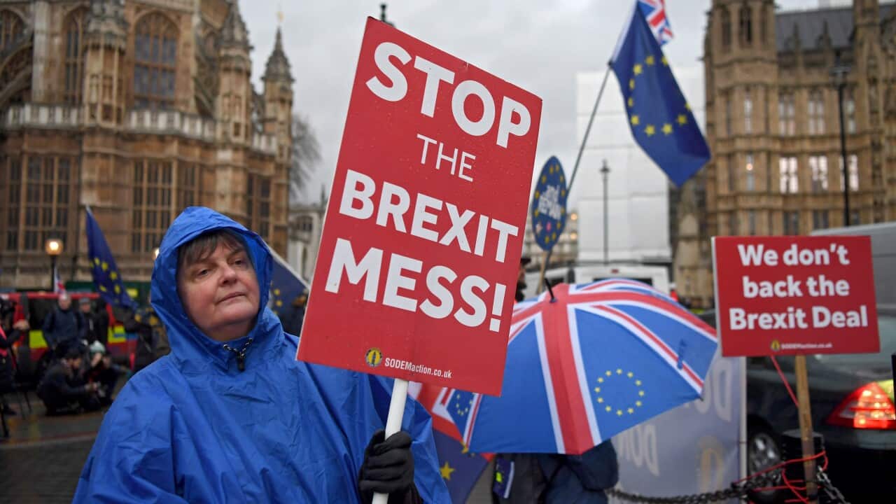 Brexit protesters shelter from a rain shower while Prime Minister Theresa May faces a no confidence vote in parliament.