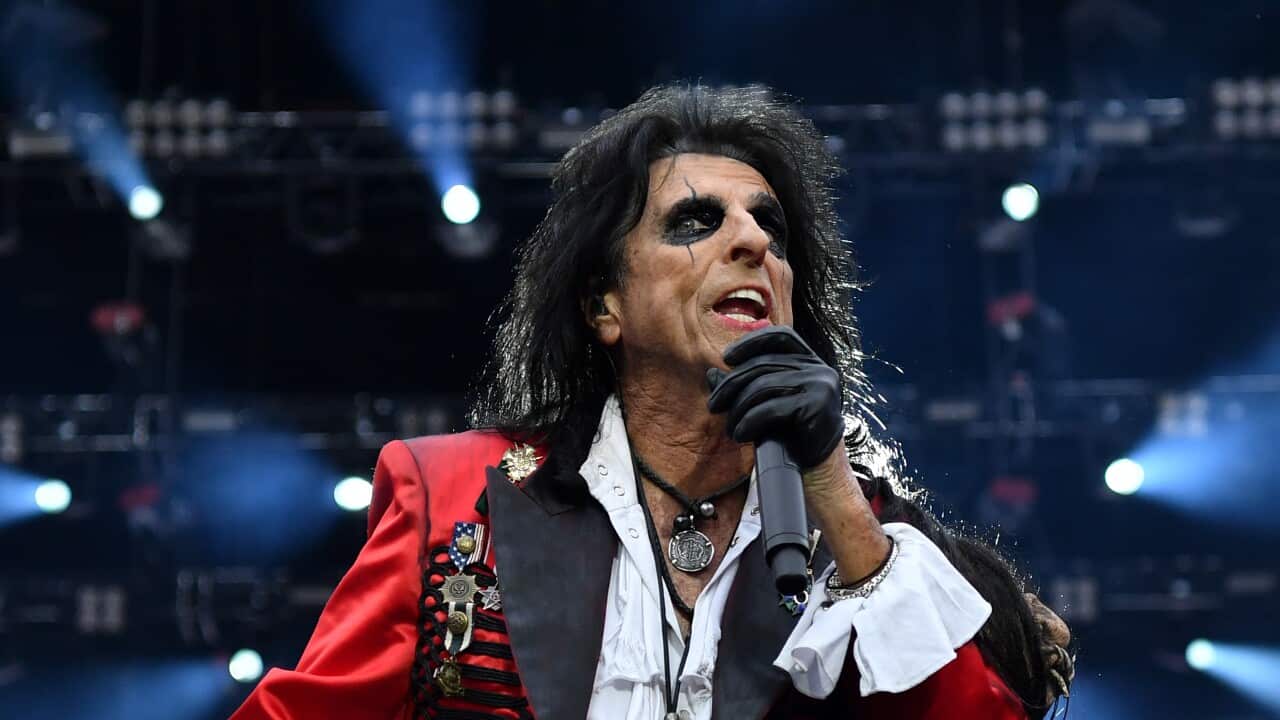 A rock singer wearning a red coat performs during a concert.