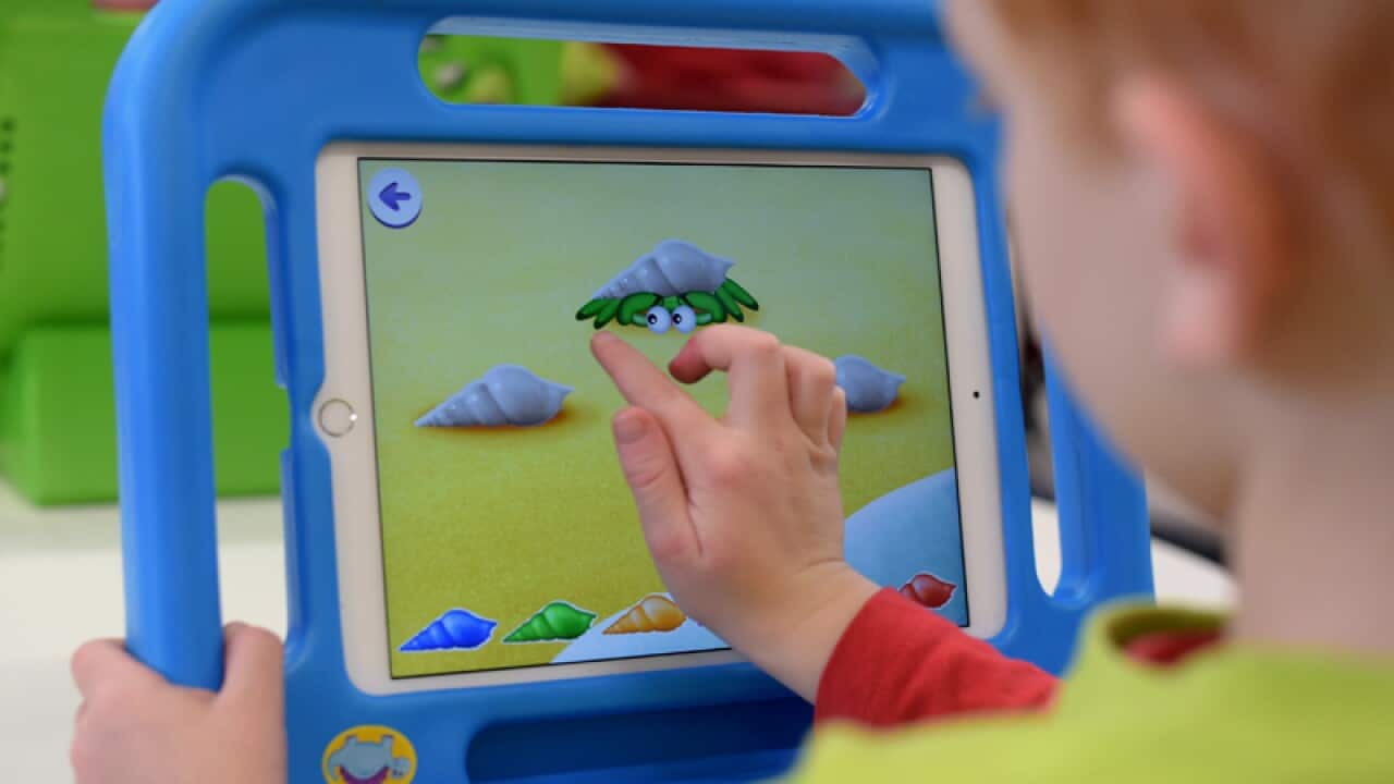 A child plays on an iPad at a early learning school