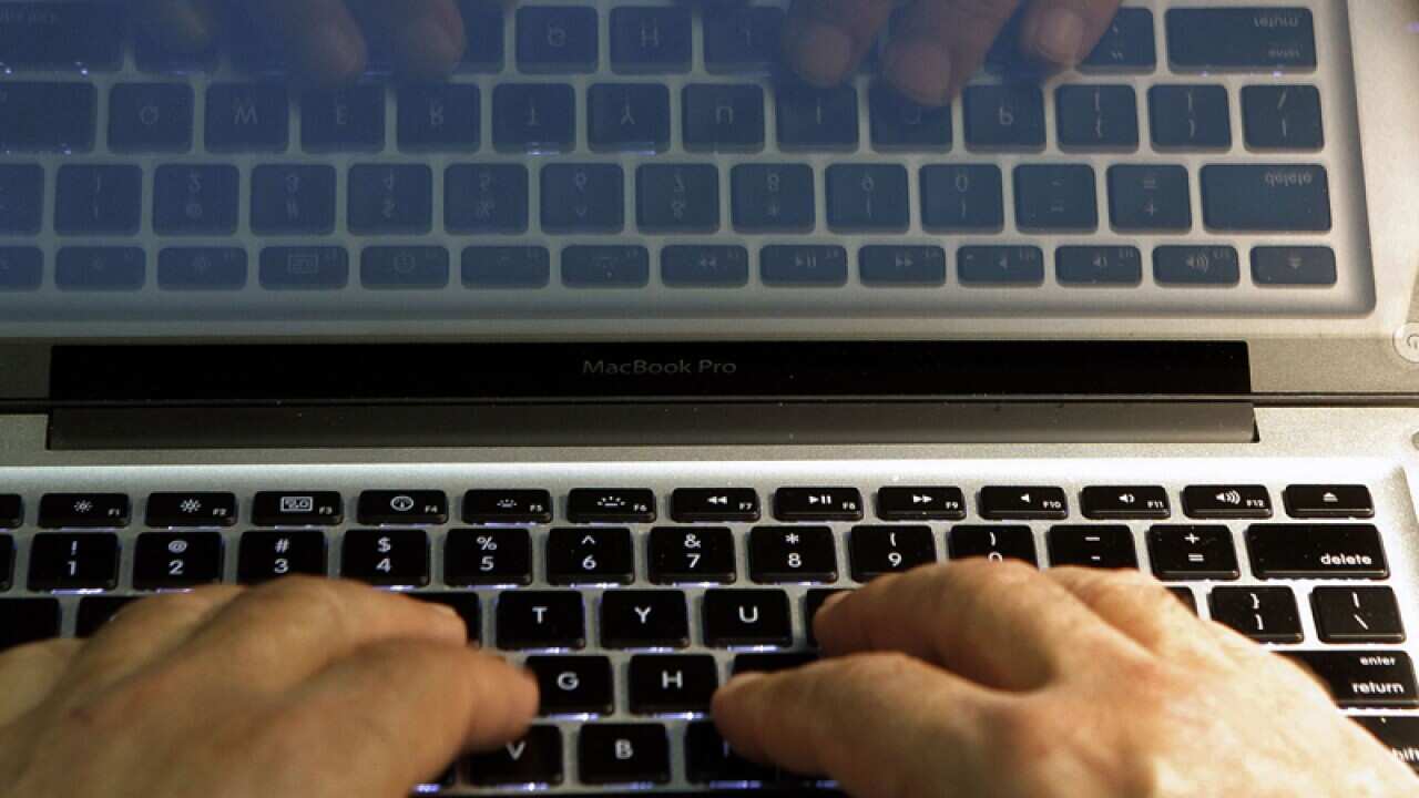 Hands type on a computer keyboard