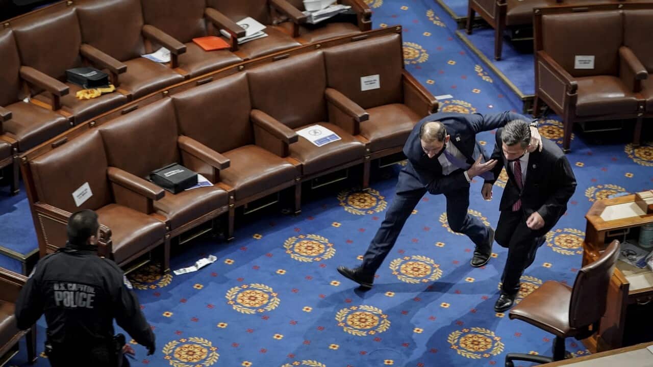 A police officer rushes a member of the House of Representatives to safety during the Jan 6 insurrection