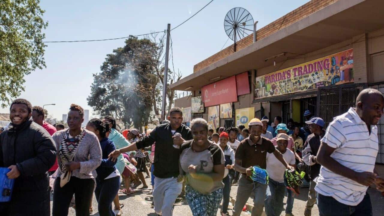 South African looters run off an alleged foreign-owned shop as South African Police officers intervene during a riot in the Johannesburg suburb of Turffontein on September 2, 2019