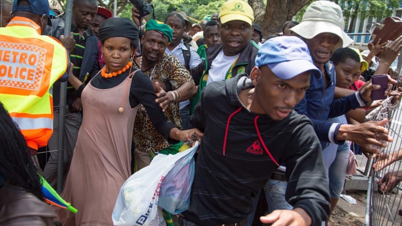 Crowds break through a barrier to view the casket of Nelson Mandela.