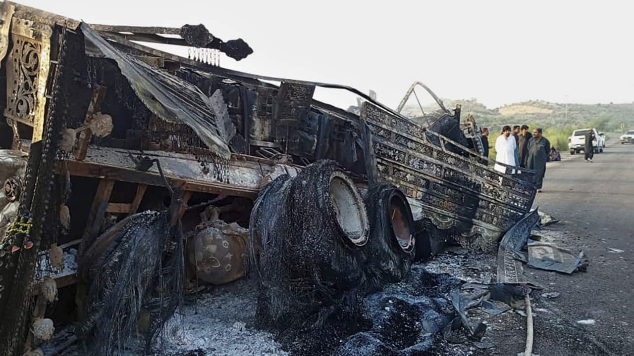 A burnt-out car is lying on the side of the road.