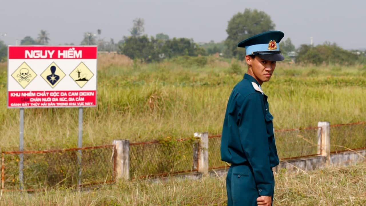 A Vietnamese soldier stands next to a hazardous warning sign by a runway at Bien Hoa air base.