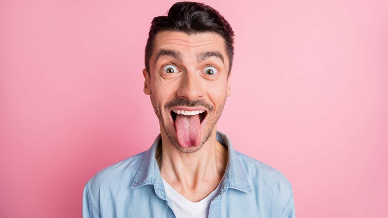 Close-up portrait of nice cheerful crazy humorous guy showing tongue out isolated over pink pastel color background