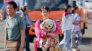 A young girl holding a teddy bear takes refuge in a temporary shelter in Buriram Province, following clashes between Thai and Cambodian soldiers