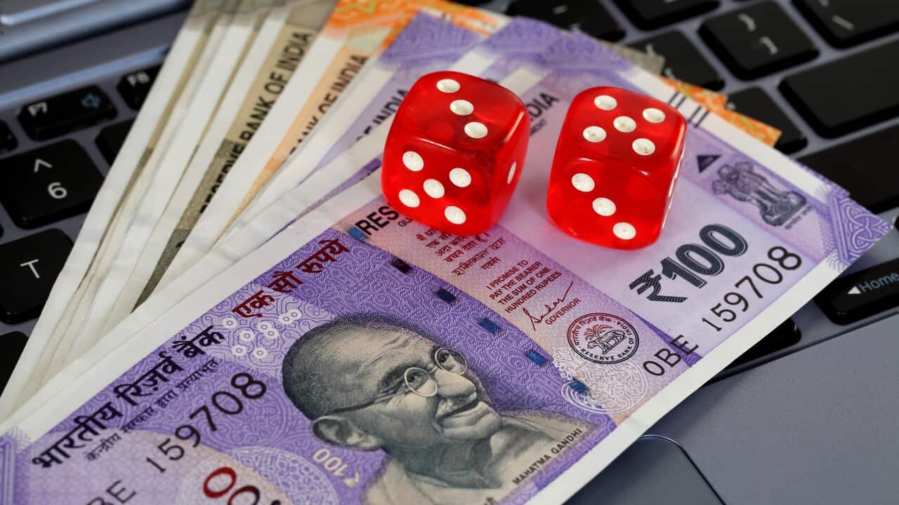 Red dice and Indian currency notes on laptop keyboard