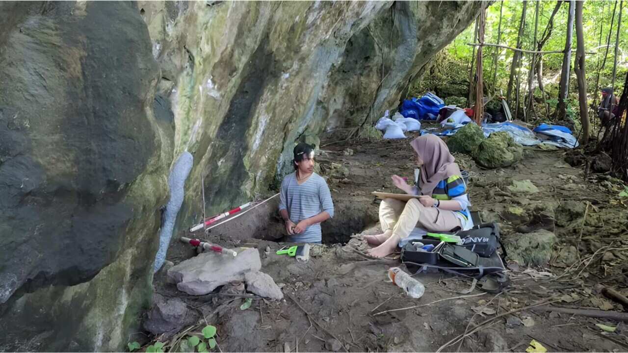A man standing in a hole while another person speaks to him.