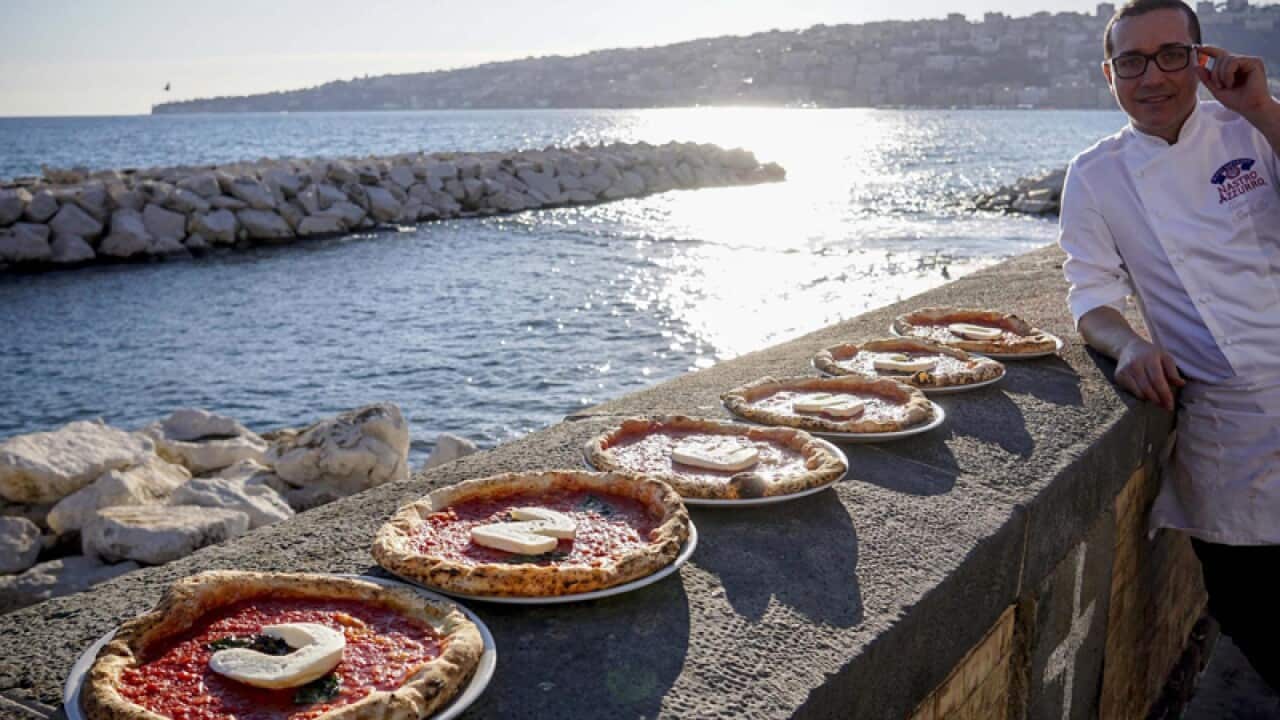 Italian chef Gino Sorbillo shows his pizza with the words 'Unesco'