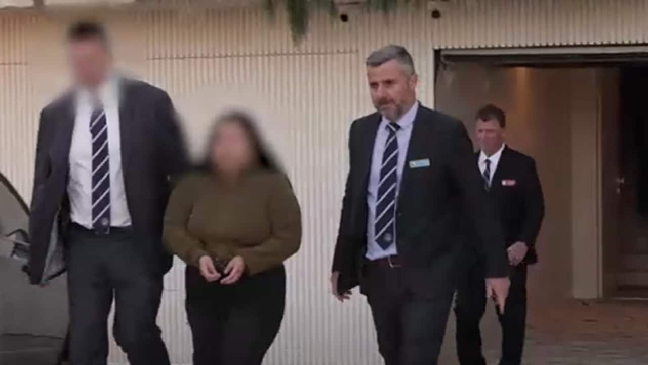Police officers escorting a woman from a property.