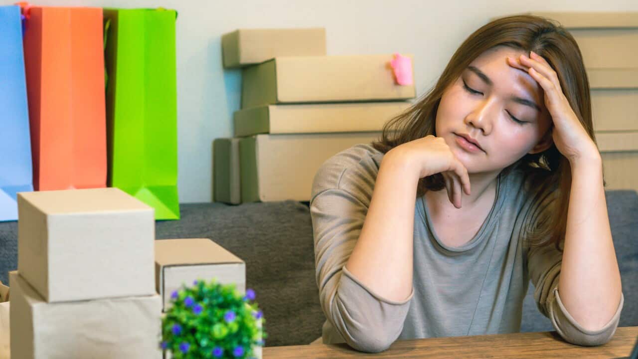 Tired Businesswoman Sitting In Head In Hand Against Boxes