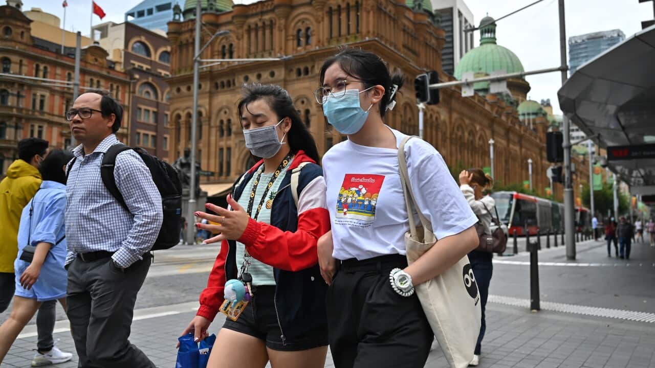 People walk along George Street in Sydney wearing masks.