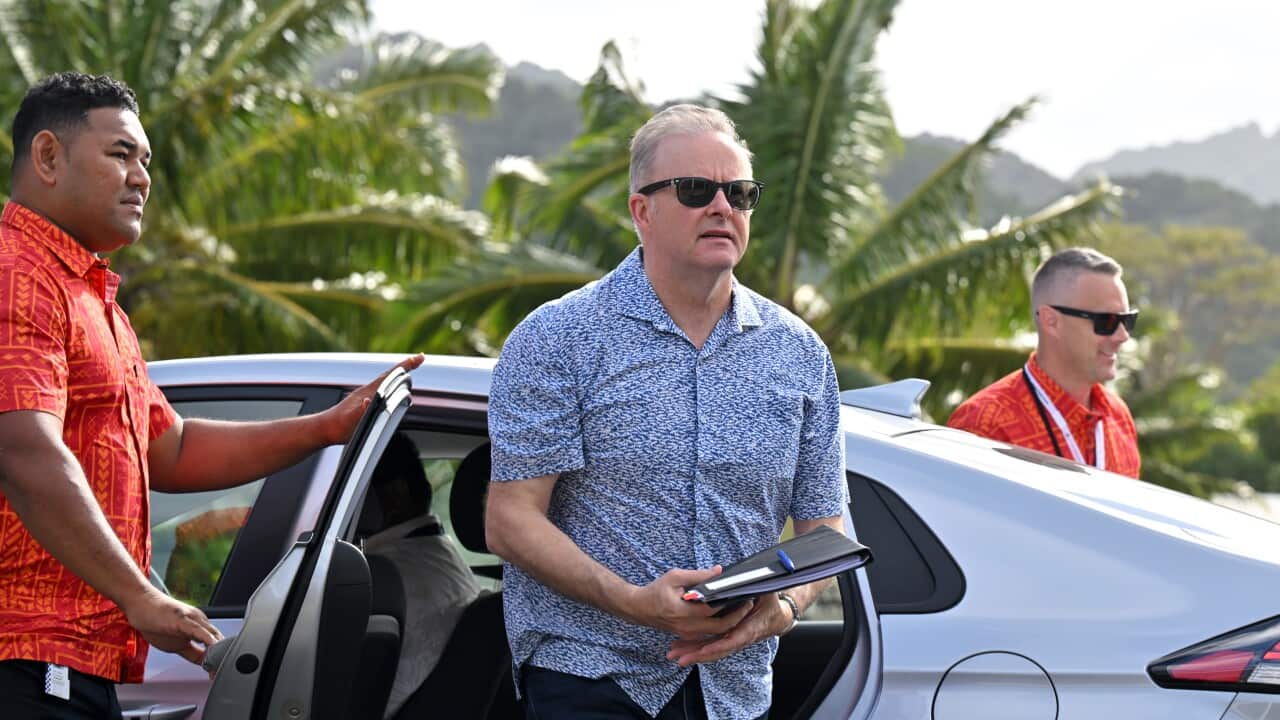Anthony Albanese steps out of a car as a man opens the door and another smiles in the background.