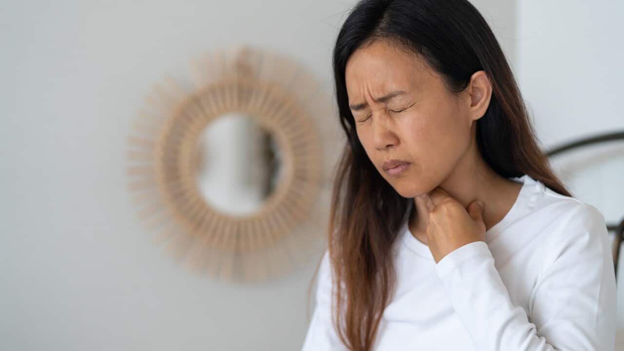 A woman touching her throat in pain
