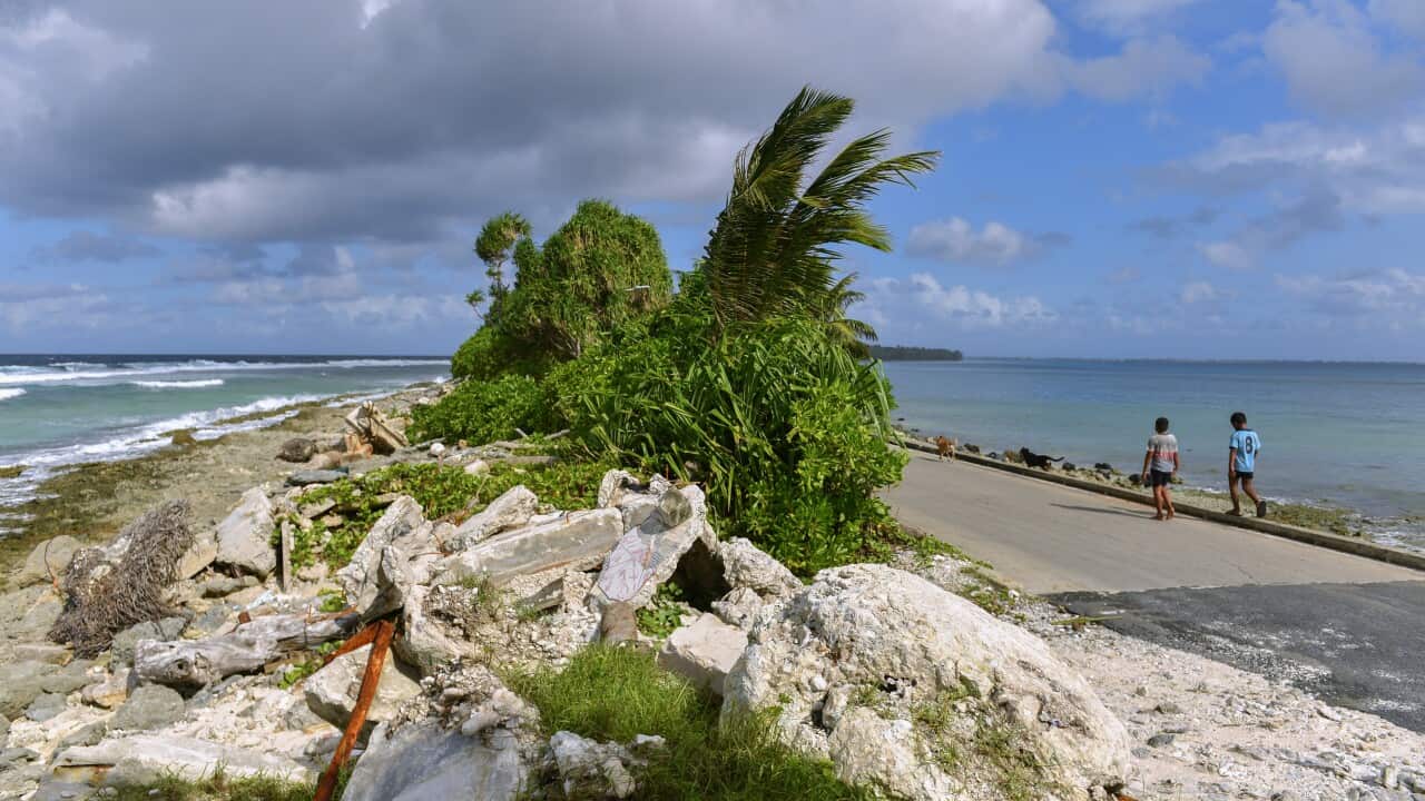 Children walk through the of the narrowest part of the island north of Funafuti, Tuvalu