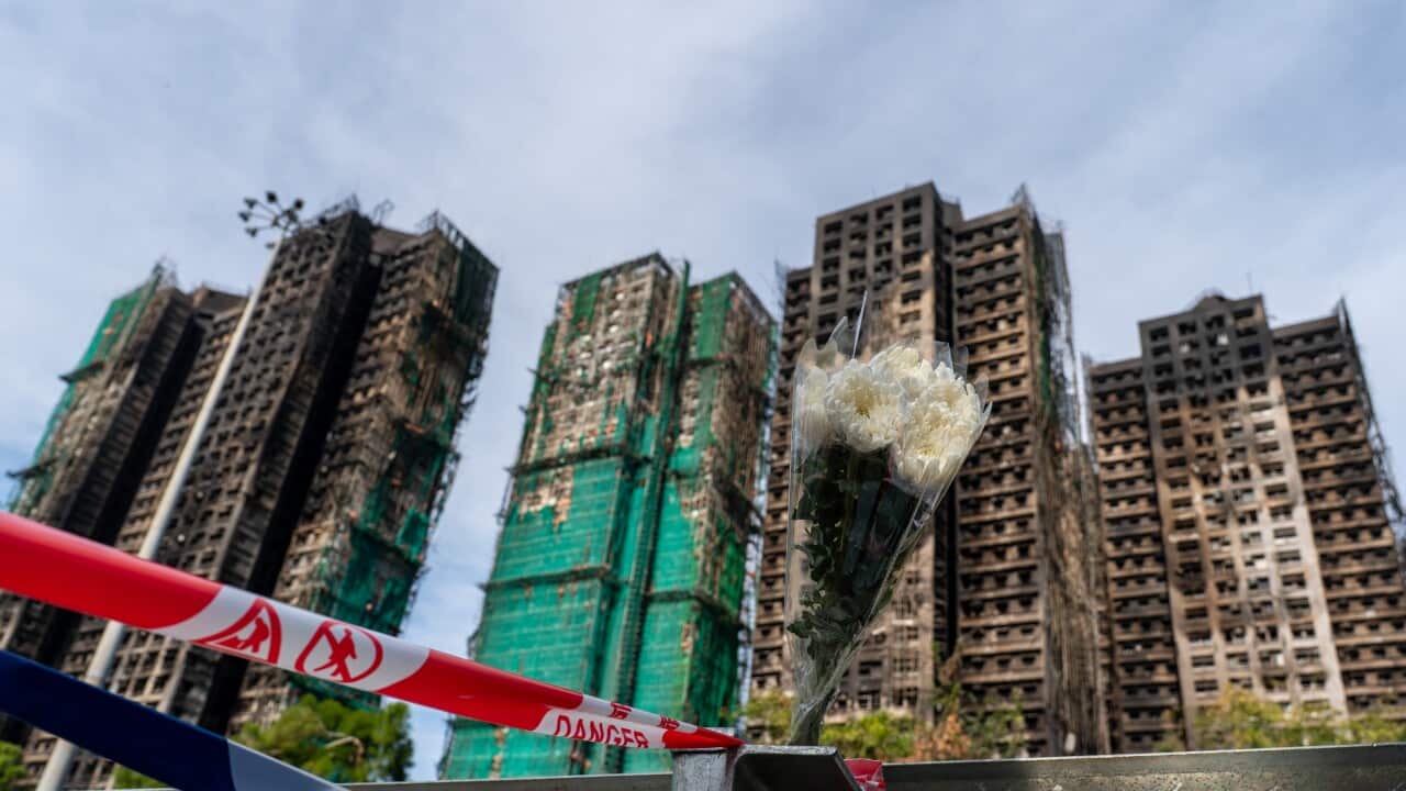 A bouquet of flowers with burned high rise buildings in the background.