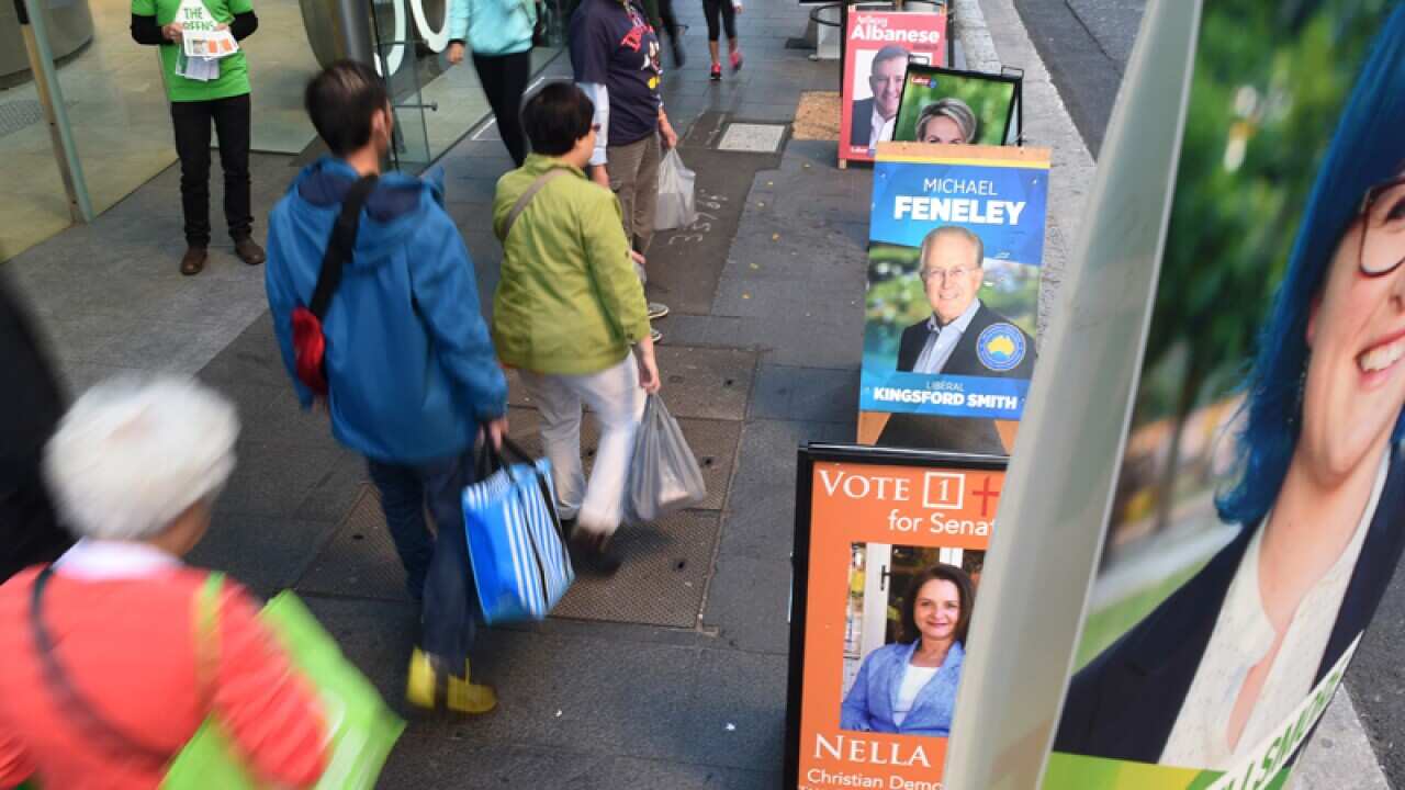 Pedestrians walk past a pre-poll voting centre in Sydney