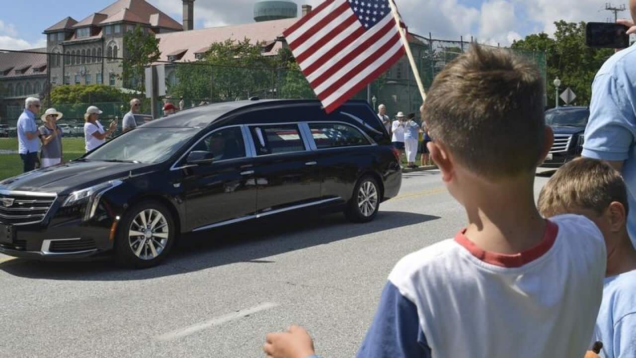 People watch as John McCain's hearse passes.