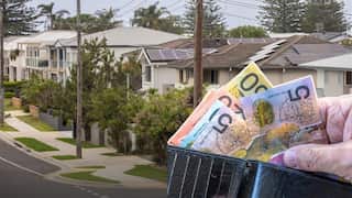 An Australian street, superimposed with a person's hand holding some Australian notes.