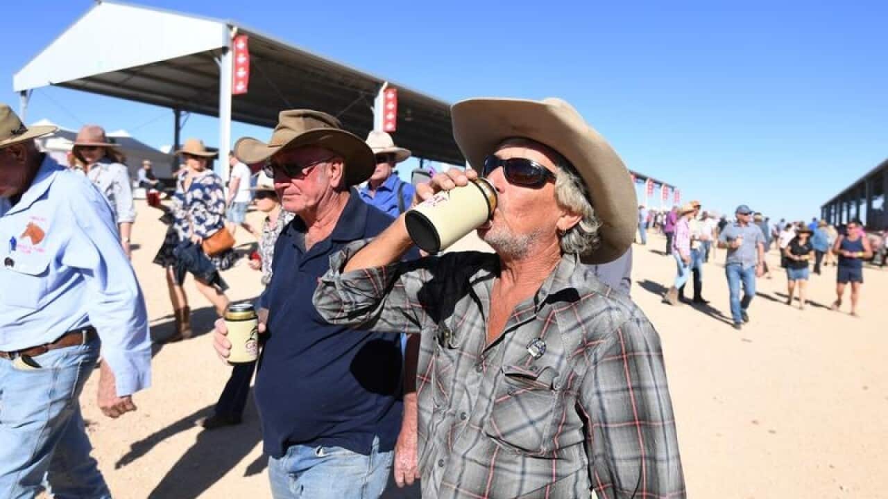 A racegoers drinks his beer at the Birdsville race.