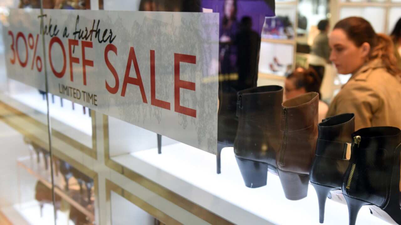 Shoppers behind a sale sign inside a retail store