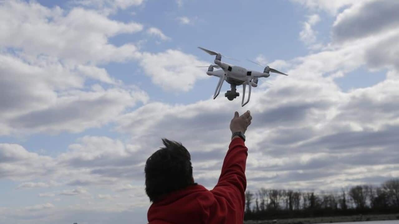 A drone operator helps to retrieve a drone.
