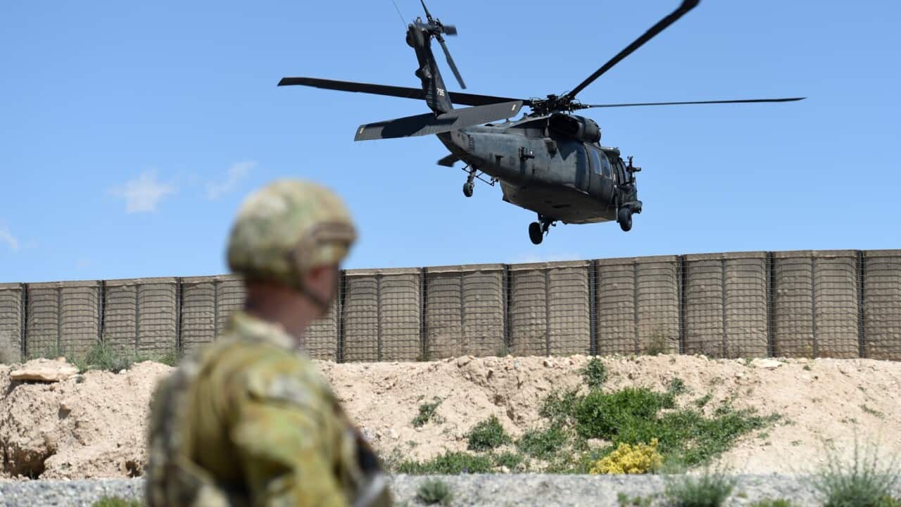 A member of the Australian Defence Force watches as a Black Hawk helicopter land at the Afghan National Army Officer Academy in Kabul, Afghanistan